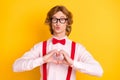 Photo portrait of geek with red hair sending air kiss showing heart symbol fingers isolated on vivid yellow background