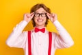 Photo portrait of geek with red hair smiling overjoyed in spectacles shirt suspenders isolated on bright yellow
