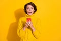 Photo portrait of girl bob hairstyle amazed shocked reading information with cellphone staring isolated on vivid yellow