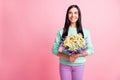 Photo portrait of girl holding floral bouquet in two hands looking at blank space isolated on pastel pink colored Royalty Free Stock Photo