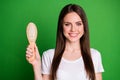 Photo portrait of girl holding hairbrush isolated on vivid green colored background