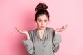 Photo portrait of girl in pajama having doubt unsure shrugging shoulders isolated on pastel pink color background