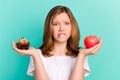 Photo portrait girl scaling sweet cupcake apple biting lip sad keeping diet isolated vivid teal color background Royalty Free Stock Photo