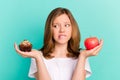 Photo portrait girl scaling sweet cupcake apple biting lip unsure got doubt isolated bright teal color background Royalty Free Stock Photo