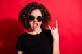 Photo portrait of girl showing rock goat sign with tongue out isolated on vivid red colored background