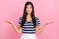 Photo portrait of girl in striped t-shirt smiling comparing copyspaces holding on hands isolated on pastel pink color