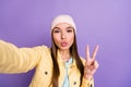 Photo portrait of girl taking selfie in casual clothes sending air kiss pouted lips v-sign isolated on pastel violet Royalty Free Stock Photo