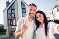 Photo portrait of happy family couple wife husband showing v-sign smiling outside new home after moving relocating Royalty Free Stock Photo