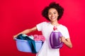 Photo portrait housewife cheerful keeping bowl of dirty clothes bottle of cleaner isolated vibrant red color background