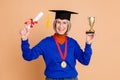 Photo portrait of lovely pensioner lady hold golden goblet medal diploma dressed stylish blue garment isolated on beige