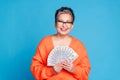 Photo portrait of lovely senior lady hold money fan dollars dressed stylish orange garment isolated on blue color Royalty Free Stock Photo