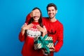 Photo portrait of lovely young spouses hold gift cover eyes surprise wear x-mas ornament red sweaters  on blue Royalty Free Stock Photo