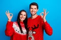 Photo portrait of lovely young spouses showing okey symbol wear x-mas ornament red sweaters  on blue color Royalty Free Stock Photo