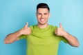 Photo portrait man in green t-shirt showing thumb up like gesture recommend happy isolated pastel blue color background