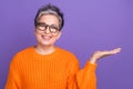 Photo portrait of marketing promoter advertiser pensioner woman holding arm empty space presentation isolated on violet