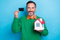 Photo portrait of mature nice mister holding small house credit card dressed stylish green clothes isolated on blue Royalty Free Stock Photo