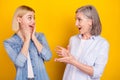 Photo portrait of mother and amazed daughter talking to each other smiling isolated vivid yellow color background