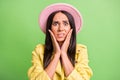 Photo portrait of nervous stressed woman touching cheekbones hands staring in pink hat isolated on vibrant green color