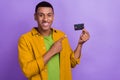 Photo portrait of nice young guy holding point credit card bank ecommerce dressed stylish yellow look isolated on violet Royalty Free Stock Photo