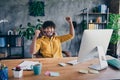 Photo portrait of nice young male wear yellow shirt celebrate work promotion raise fist living room interior loft Royalty Free Stock Photo