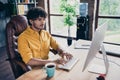 Photo portrait of nice young male wear yellow shirt typing keyboard look monitor work sit table living room interior Royalty Free Stock Photo