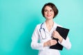 Photo portrait of nurse smiling hugging clipboard wearing white uniform looking copyspace isolated vibrant teal color