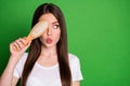 Photo portrait of pouting girl covering one eye with hairbrush looking at blank space isolated on vivid green colored