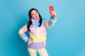 Photo portrait of pouting girl taking selfie holding phone in one hand isolated on pastel blue colored background