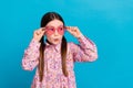 Photo portrait of pretty schoolkid touch pink heart sunglass dressed stylish pink flower print outfit isolated on blue Royalty Free Stock Photo