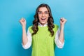 Photo portrait of pretty young girl eyeglasses raise fists celebrate promotion wear trendy green outfit isolated on blue Royalty Free Stock Photo