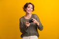 Photo portrait of pretty young girl play play station joystick dressed stylish knitted khaki outfit isolated on yellow Royalty Free Stock Photo