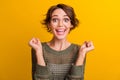 Photo portrait of pretty young girl raise fists excited wear trendy knitwear khaki outfit  on yellow color Royalty Free Stock Photo