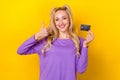 Photo portrait of pretty young girl thumb up hold credit card ebanking client wear trendy purple look isolated on yellow