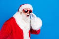 Photo portrait of retired old man cover mouth share secret wear trendy santa claus costume coat isolated on blue color