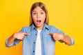 Photo portrait of sad upset schoolgirl pointing on herself asking surprised wearing denim shirt isolated on bright