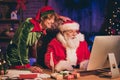 Photo portrait of santa claus and elf browsing internet on desktop Royalty Free Stock Photo