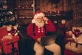 Photo portrait santa wearing glasses sweater browsing internet with laptop sitting in decorated room Royalty Free Stock Photo