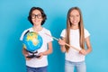 Photo portrait schoolboy schoolgirl doing homework keeping globe pointer isolated pastel blue color background