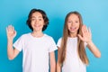 Photo portrait schoolboy schoolgirl waving hands greeting friends isolated pastel blue color background