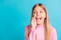 Photo portrait of schoolgirl with blonde hair telling secret quietly looking at blank space isolated on vibrant teal