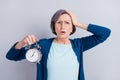 Photo portrait of senior business woman keeping alarm clock late for deadline stressed isolated on grey color background
