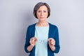 Photo portrait of serious senior woman keeping glasses wearing blue cardigan isolated on grey color background copyspace Royalty Free Stock Photo