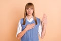 Photo portrait of serious woman in formal wear keeping hand on chest promising isolated on pastel beige color background