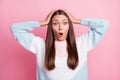 Photo portrait of shocked amazed girl with opened mouth keeping head with hands isolated on pastel pink color background