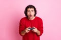 Photo portrait of shocked man holding videogame controller in two hands isolated on pastel pink colored background Royalty Free Stock Photo