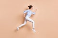 Photo portrait side view of girl running jumping up isolated on pastel beige colored background Royalty Free Stock Photo