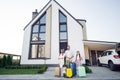 Photo portrait of smiling big full family with small kids keeping baggage near car relocating ready to enter home Royalty Free Stock Photo