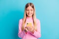 Photo portrait of smiling blonde little girl using smartphone app typing texting isolated on vivid turquoise color Royalty Free Stock Photo