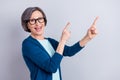 Photo portrait of smiling cheerful elder woman with grey hair pointing fingers blank space isolated on grey color Royalty Free Stock Photo