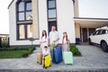 Photo portrait of smiling couple wife husband with small kids keeping suitcases outside home ready for travel Royalty Free Stock Photo